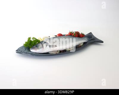 Whole fresh sea bass with salad isolated on white. Stock Photo