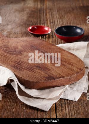Empty rustic wooden cutting board with linen and bowls. Stock Photo