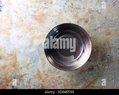 Empty rustic ceramic bowl from above on textured rustic metallic background, ideal for soup and salad photography Stock Photo