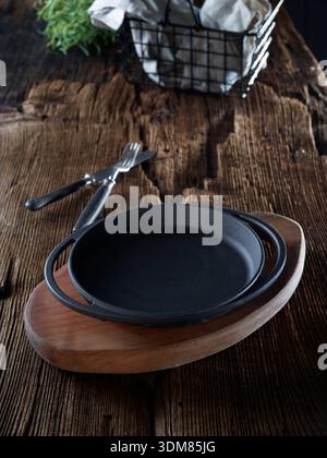 Rustic kitchen still life with black cast iron skillets, cooking utensils and ingredients Stock Photo