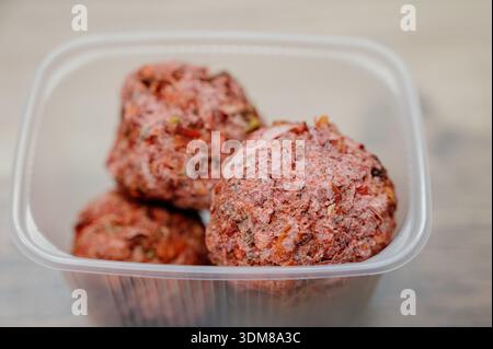 Meatballs with added herbs and paprika in food packaging on a light background. Spiced balls prepared for cooking in a plastic box Stock Photo