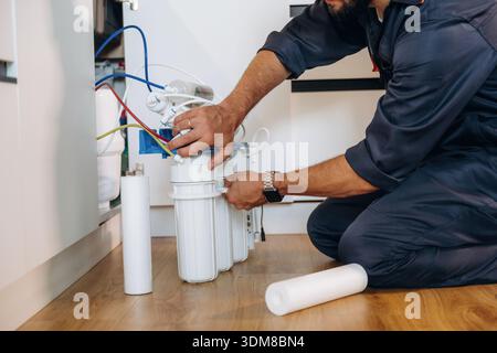 Installing new filters. Plumber working in the kitchen under the sink. Stock Photo