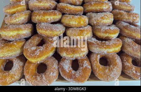 Close up of freshly fried donuts covered with sugar on wooden board Stock Photo
