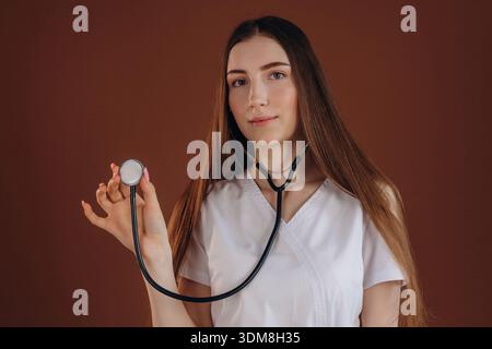 Holding the stethoscope. Female doctor is in the studio. Stock Photo