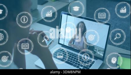 Watching viewer following presenter on laptop at desk, with digital icons and green notebook Stock Photo