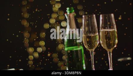 Displaying two tall champagne flutes filled with bubbles on bar, with green bottle with foil neck Stock Photo