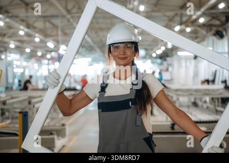 Big frame in hands. Woman is in the window making factory. Stock Photo