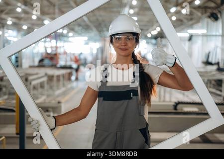 Empty frame is in hands. Woman is in the window making factory. Stock Photo