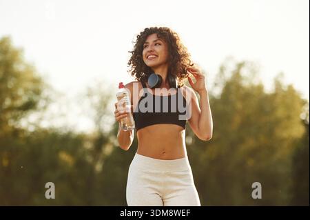 Good attitude, standing. Young fitness woman is on the field outdoors. Stock Photo