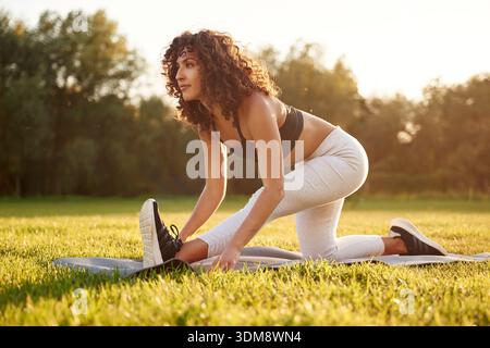 Stretching the legs. Young fitness woman is on the field outdoors. Stock Photo
