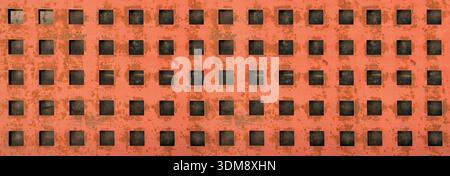 Rusty orange metal surface showing repeating square holes, creating a textured background Stock Photo