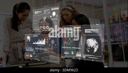Analyzing team of four in office wearing business wear, leaning over laptop with AR dashboards Stock Photo
