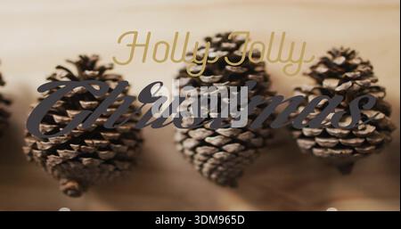 Displaying three brown pine cones resting on light wooden plank, with Holly Jolly Christmas script Stock Photo