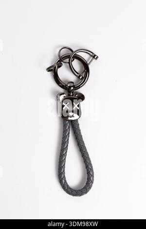Close up of black metallic bear keychain with braided leather loop isolated on white background Stock Photo