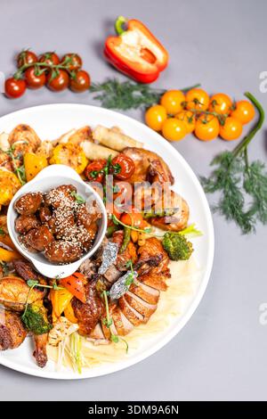 Top view of chicken platter with vegetables sauces and decorative elements on grey background Stock Photo