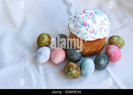 Festive Easter kulich on a light tablecloth with painted eggs, classic Easter symbol. Stock Photo