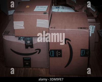 Stack of Amazon Prime delivery boxes on a wooden floor, symbolizing online shopping, e-commerce growth, and modern consumer convenience. Stock Photo
