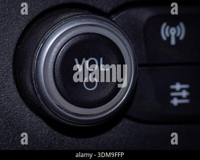 Close-up of a car stereo volume and power control knob showing the “VOL” button design, symbols, and texture under soft studio light. Stock Photo