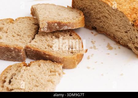 Sliced homemade bread on white background closeup. Fresh bakery product and traditional food concept with rustic loaf pieces isolated. Stock Photo
