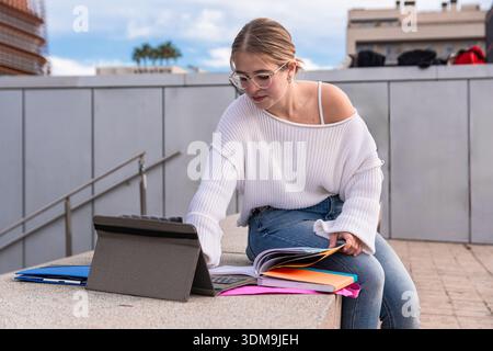 Young woman student using tablet and notebook on campus stairs Stock Photo