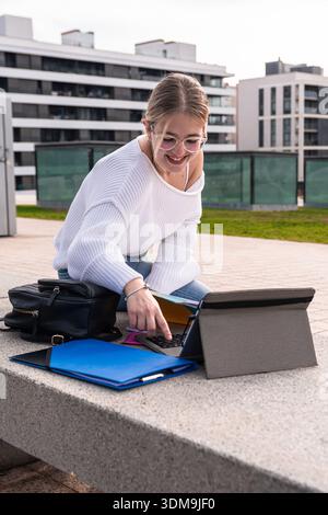 Young woman student using laptop studying on campus pavement Stock Photo
