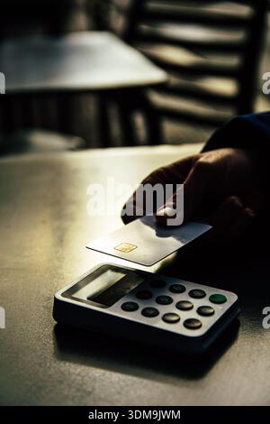 Hand making contactless payment with credit card at terminal Stock Photo