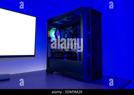 High performance desktop computer with rgb cooling fan, liquid cooling tubes and graphics card, illuminated in blue lighting against minimal backgroun Stock Photo