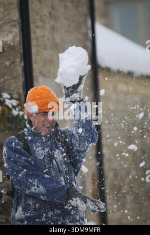 Father throwing snowball during winter snowfall in residential street in Oxfordshire, England, UK. Stock Photo