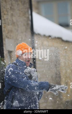 Father throwing snowball during winter snowfall in residential street in Oxfordshire, England, UK. Stock Photo