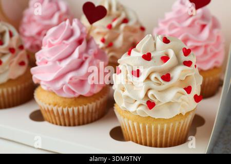 Happy Valentine's Day. Tasty cupcakes with red hearts in box, closeup Stock Photo