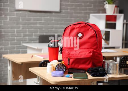 Emergency backpack with necessities on desk in classroom Stock Photo