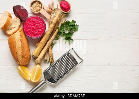 Bowl of horseradish sauce with beet, ingredients and grater on white wooden background Stock Photo