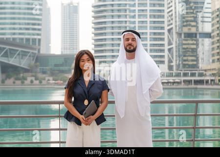 Portrait of a multicultural business team, a Middle Eastern man and an Asian woman, during a walk in a corporate district. Stock Photo