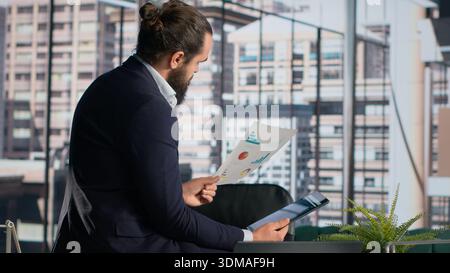 Documents analysis, businessman reviews company metrics, KPIs and reports, business administration and financial management. CEO decision making, development strategy, corporate insights. Stock Photo