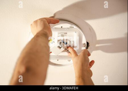 Closeup man's hands replacing ceiling light fixture with copy space Stock Photo
