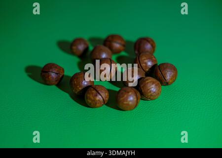 Macadamia Nuts Scattered on a Green Surface Stock Photo