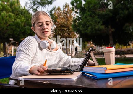 Young woman student studying outdoors on campus with tablet Stock Photo