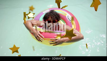 Leaning man in swimsuit, red sunglasses, smiling and floating in sunny pool with donut, stars Stock Photo
