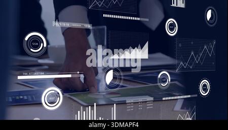 Pointing man wearing dark suit and white cuff at meeting table with charts, tablet, AR overlays Stock Photo