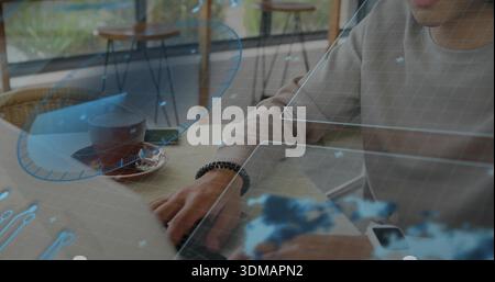 Typing man wearing ribbed-shirt bracelet in cafe, using laptop, smartwatch, UI-overlays, copy space Stock Photo