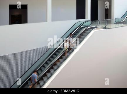 People on escalator in building interior Stock Photo
