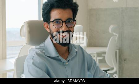 Indian Muslim business man entrepreneur working laptop in modern office looking at camera smiling executive businessman manager programmer employer Stock Photo