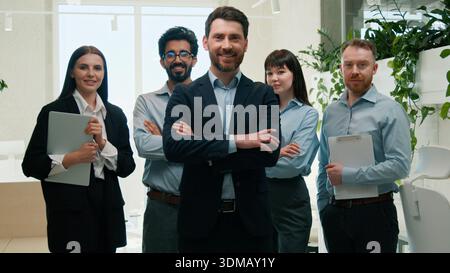 Confident business team multiethnic businessmen businesswomen posing crossed arms males females leader boss group indoor corporate office happy Stock Photo