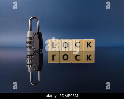 Combination padlock alongside wooden letter blocks spelling the word LOCK. Stock Photo