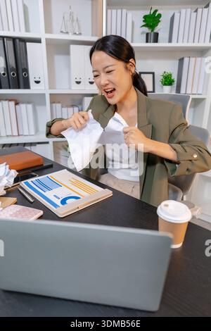 Stressed businesswoman dealing with heavy work pressure, reacting emotionally while reviewing reports and facing tight deadlines, highlighting workpla Stock Photo