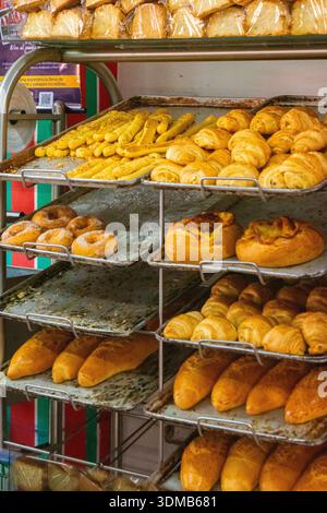 A variety of breads and pastries neatly arranged on metal trays in a bakery. The golden croissants and doughnuts catch the eye. Stock Photo