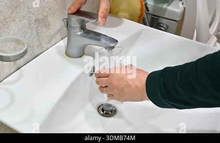 Close up of filling glass with water from sink faucet in bathroom Stock Photo