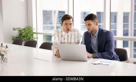 Two focused men working together on presentation using laptop Stock Photo
