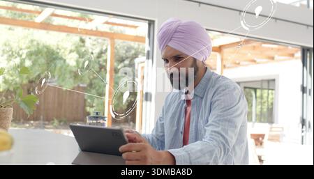 Using man wearing purple turban and striped shirt tapping tablet at kitchen counter with folio case Stock Photo