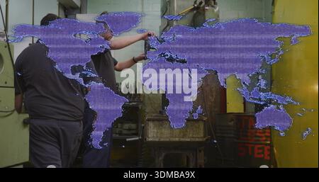 Adjusting two workers in dark uniforms operating wall-mounted control at metal shop, purple map Stock Photo